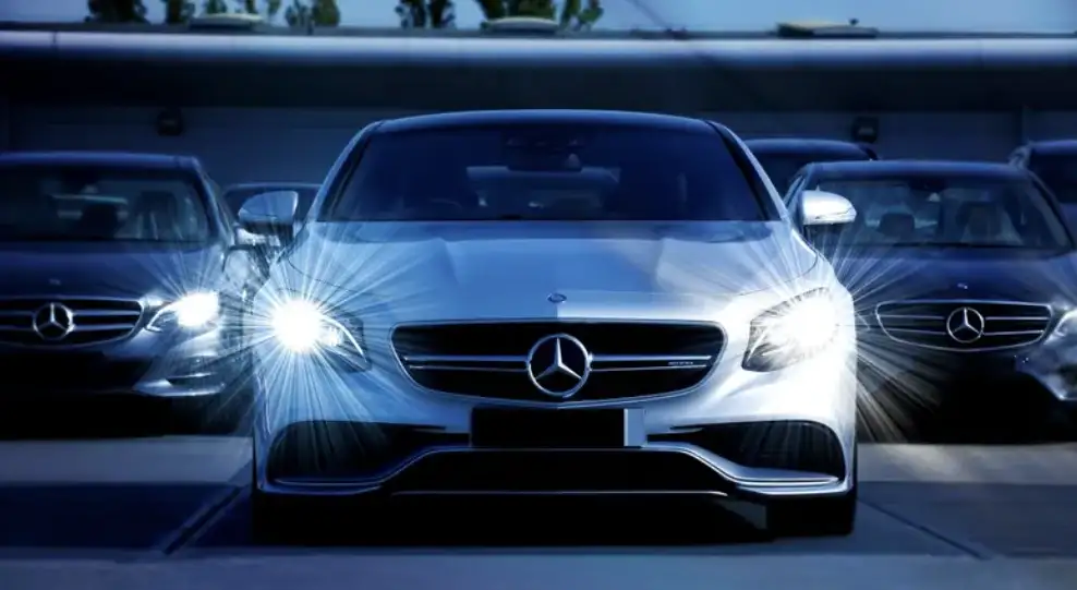 Automóvil plateado con los faros encendidos delante de otros vehículos