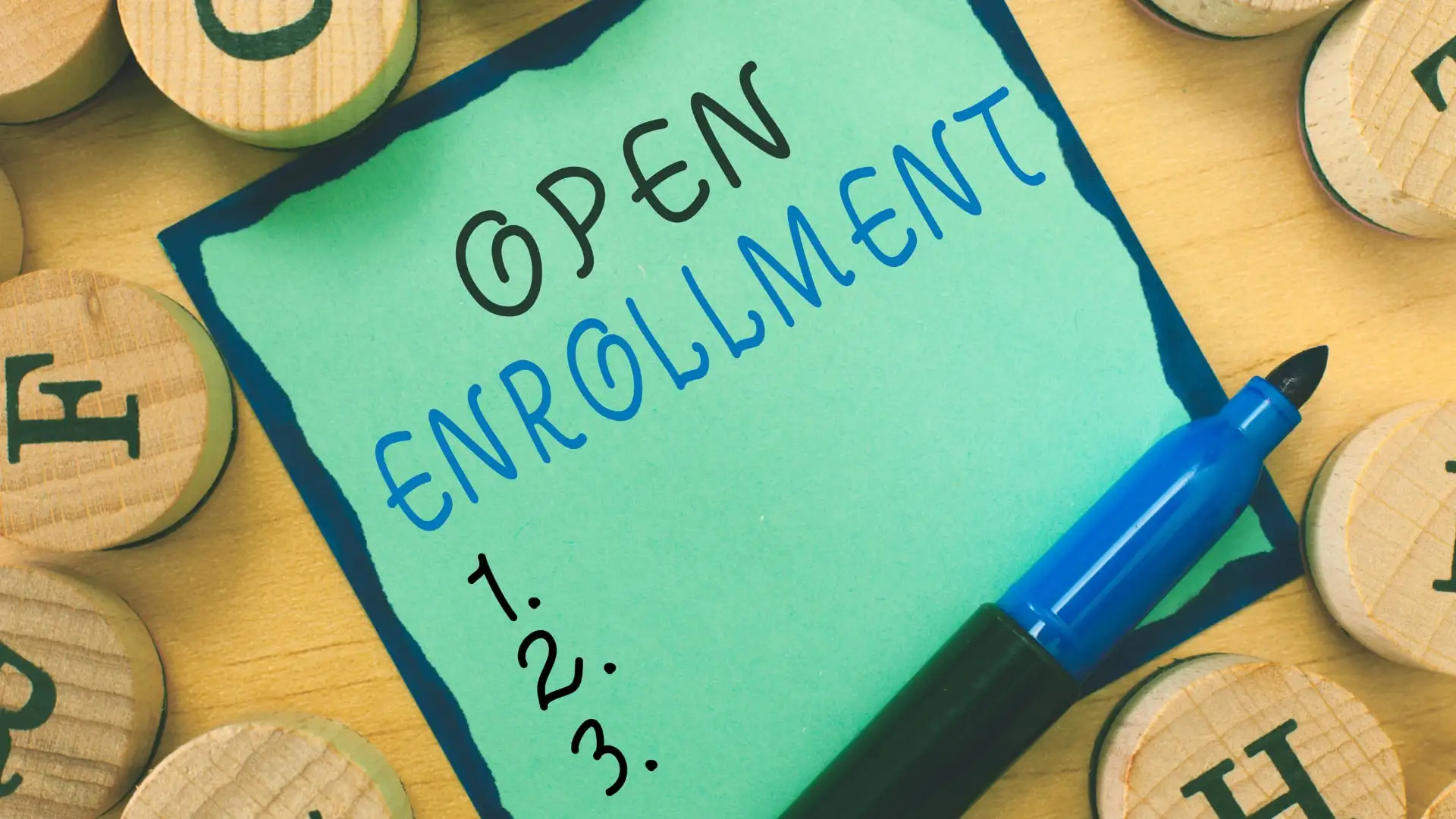 Nota verde con las palabras Open Enrollment y una lista numerada junto a un rotulador azul